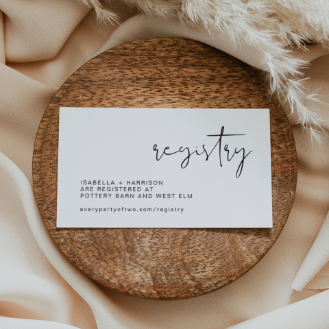 A wedding registry card displayed on a wooden block, wrapped in silks.