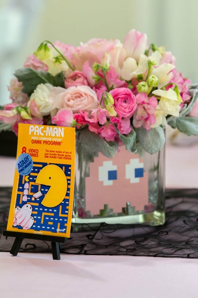 A Pac-Man themed centerpiece with flowers and Pinky the ghost. The box for the Atari 2600 version of Pac-Man is stood in front of it.