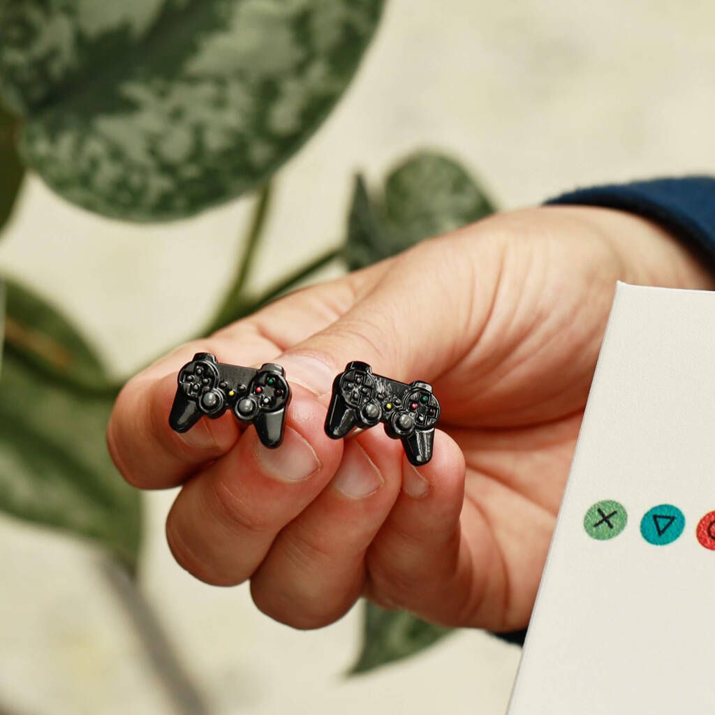 A pair of cufflinks modeled after a modern gaming controller held in a man's hand.