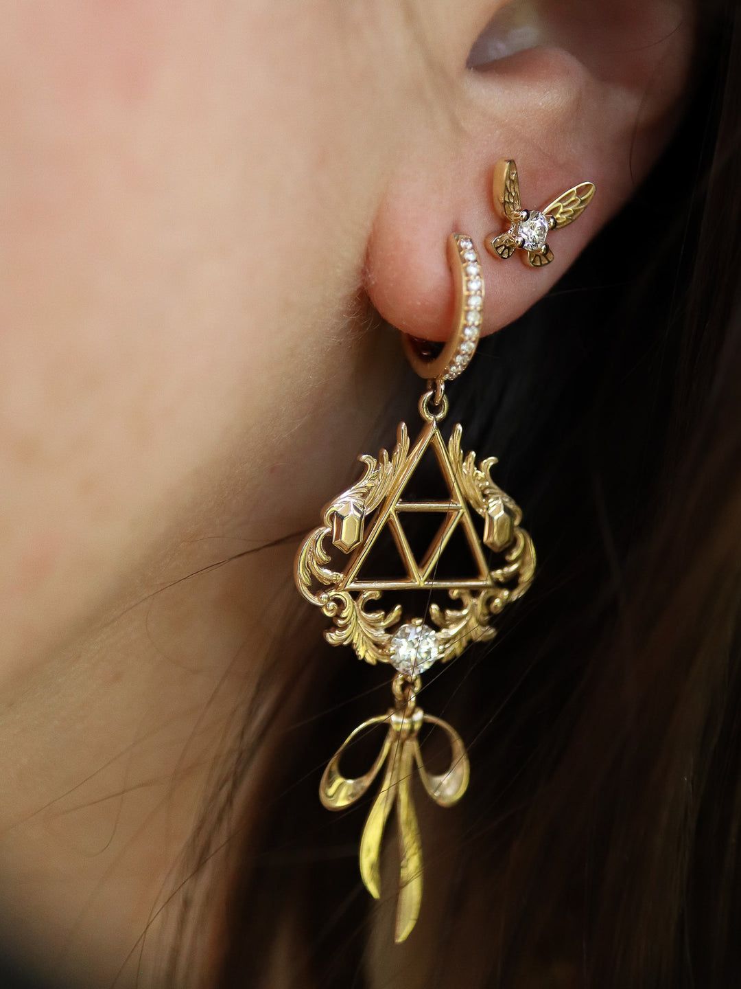 An earring modeled after The Legend of Zelda series is shown hanging from a woman's ear.