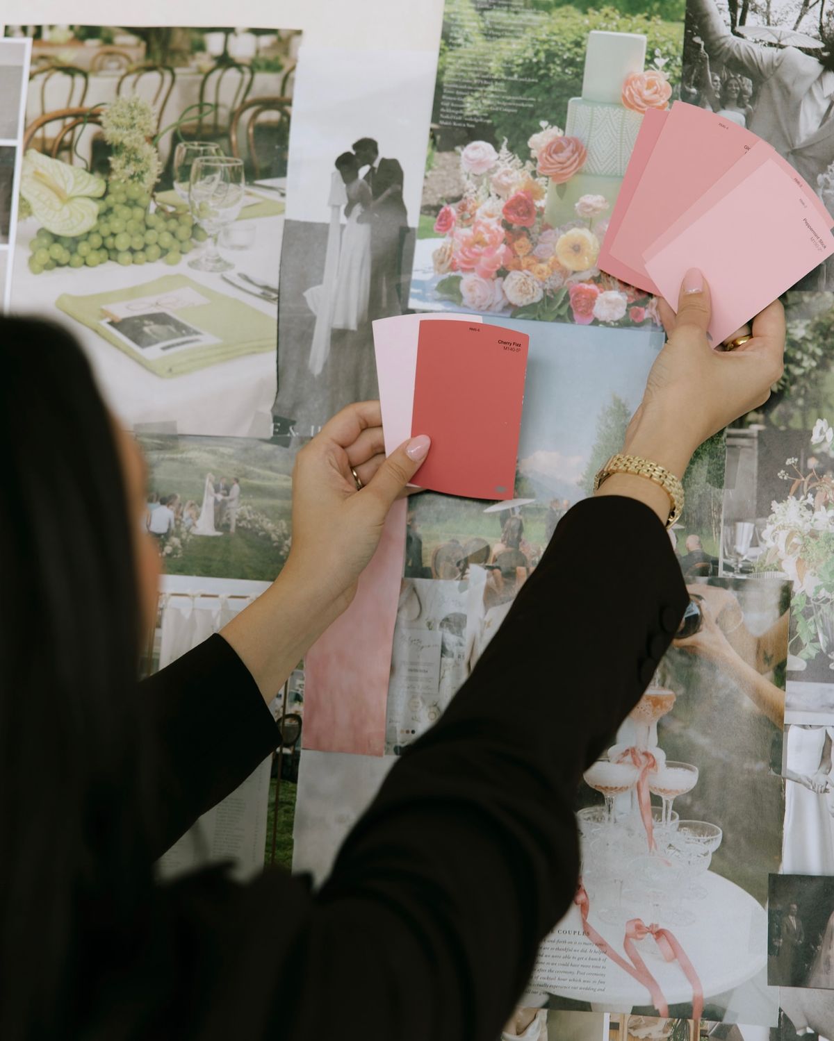 A wedding designer compares color swatches against wedding imagery pinned up on a wall.