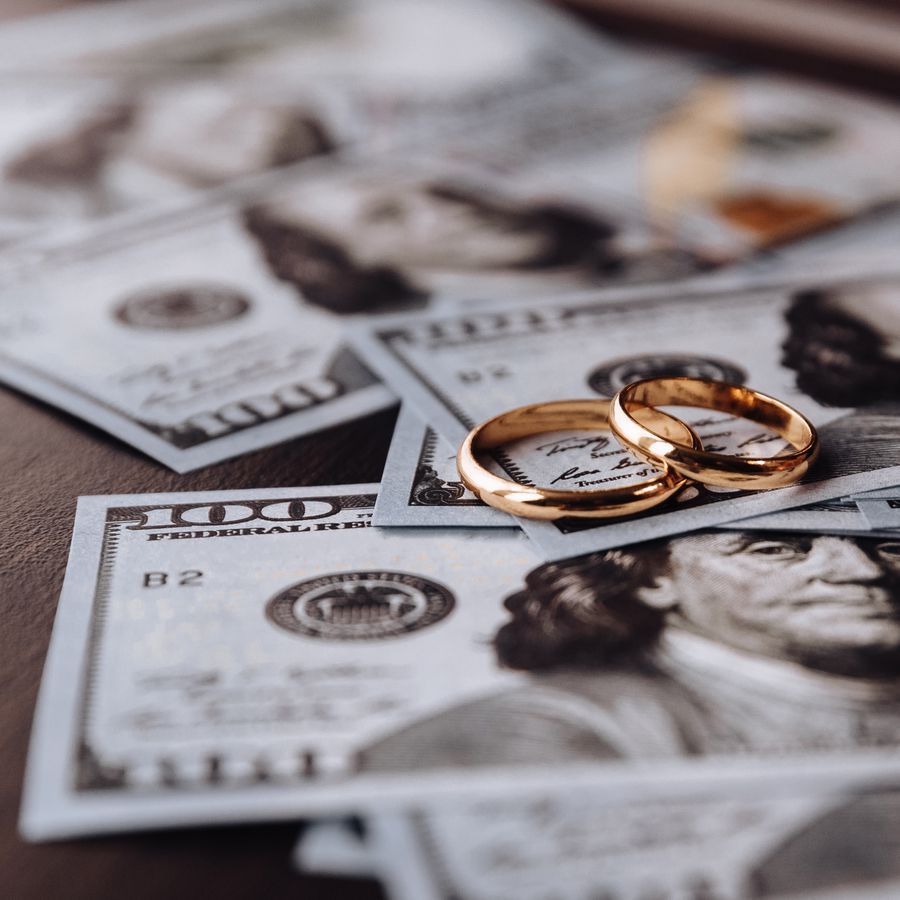 Wedding bands placed on top of hundred dollar bills.