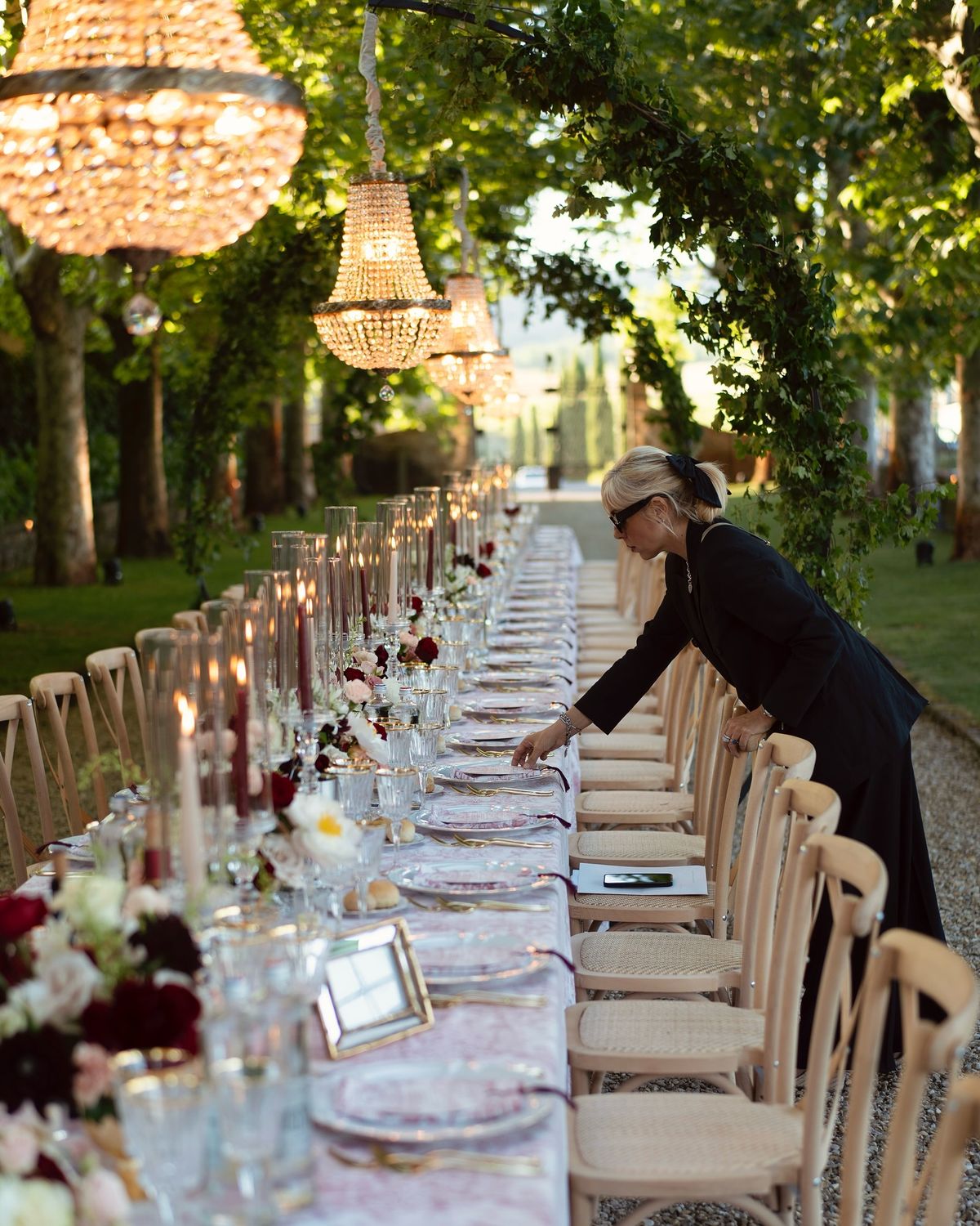 A wedding facilitator works to double-check all of the placements on the tablescape at a wedding venue.