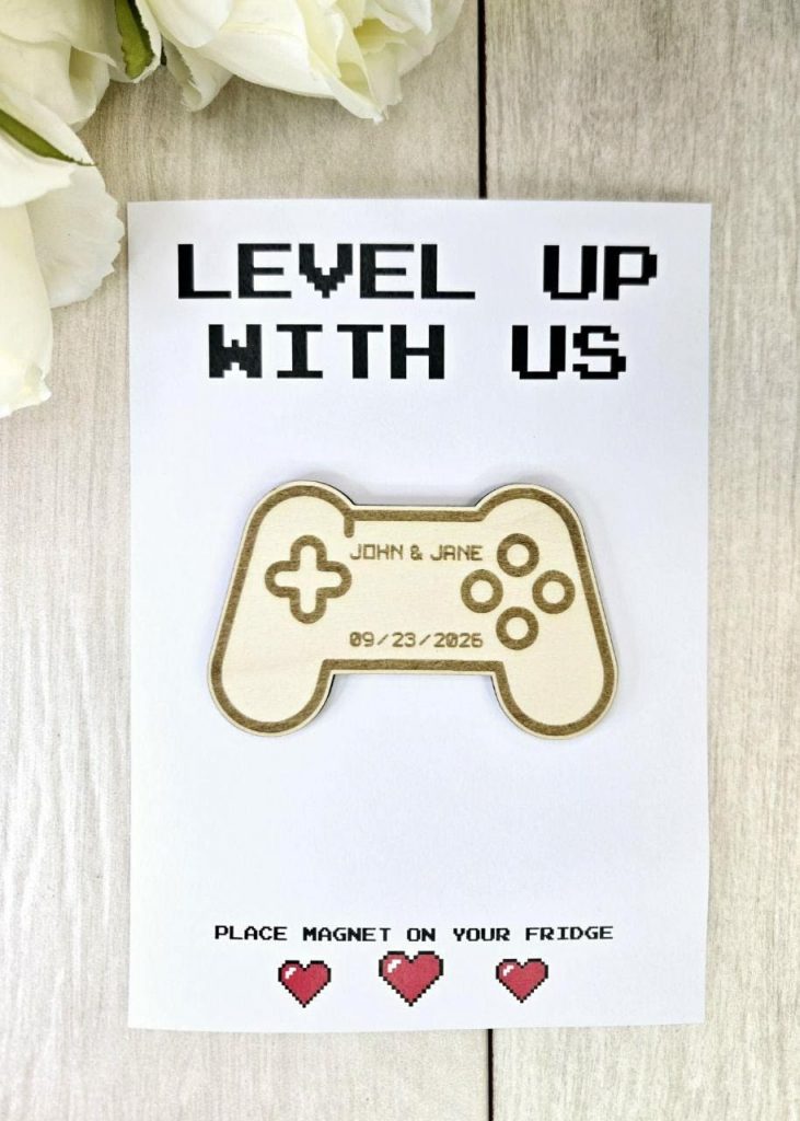 A video game-themed Save the Date magnet featuring a controller lying on a wooden background.