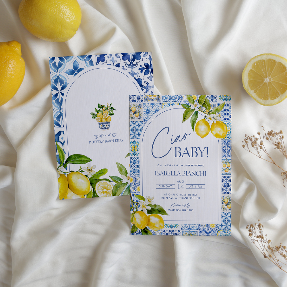 A Ciao Baby Italian lemon-themed baby shower invitation suite with blue and white Mediterranean tile pattern border, watercolor lemon illustrations, and white blossoms, displayed with fresh lemons on cream fabric.