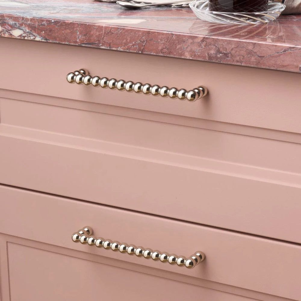 A pink granite counter top and pink drawers with silver beaded-style fixtures as handles.